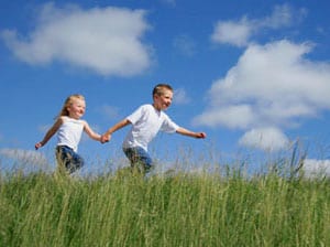 Photo of boy an girl running hand in hand in the grass